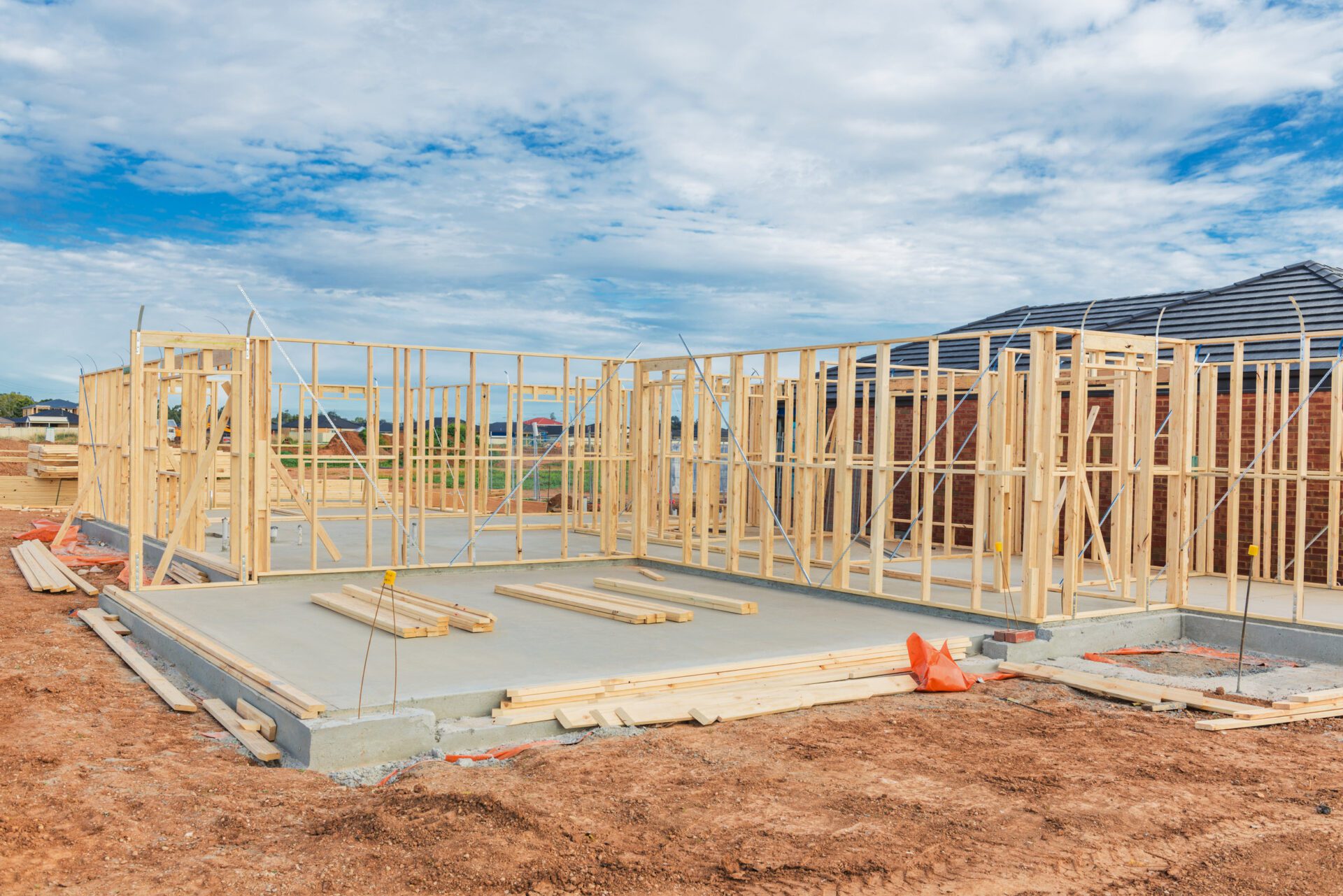 New residential construction home framing against a blue sky.